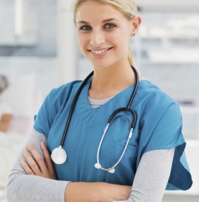 Young smiling doctor standing in hospital with colleagues talking to patient in background